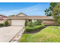 Beautiful single-story home featuring stone accents, a tile roof, manicured landscaping, and an attached two-car garage at 7032 Pelican Island Dr, Tampa, FL 33634