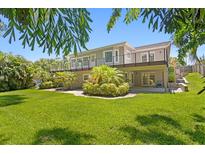 A lush green lawn leads up to a two-story house with a deck overlooking a meticulously landscaped backyard, perfect for outdoor enjoyment at 80 Sycamore Ct, Palm Harbor, FL 34683