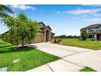 Beautiful home with a spacious driveway, green lawn, and scenic water view in a quiet neighborhood at 11878 Thicket Wood Dr, Riverview, FL 33579
