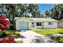 Charming single-story home featuring a well-manicured lawn, blue garage door and coordinated trim at 1573 Cumberland Ln, Clearwater, FL 33755