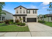 Charming two-story home featuring a landscaped yard, two-car garage, and a basketball hoop on the driveway at 1844 Odiorne Point Ln, Wesley Chapel, FL 33543