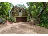 Unique two-story home featuring a wooded lot, attached garage, and interesting roofline at 2279 Ranchette Ln, Dunedin, FL 34698