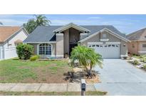 Charming single Gathering home boasting mature landscaping, a two-car garage, and inviting curb appeal at 332 Wood Dove Ave, Tarpon Springs, FL 34689
