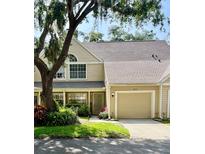 Inviting tan two-story townhome featuring an attached garage and lush landscaping at 3615 Pine Knot Dr, Valrico, FL 33596
