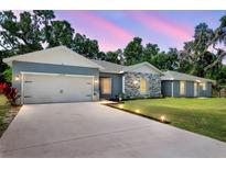 Charming single-story home showcasing stone accents, a well-manicured lawn, and an inviting two-car garage at 37230 Poinsettia Ave, Dade City, FL 33525