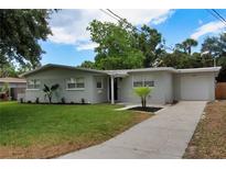 Charming single-story home featuring a well-manicured lawn and a long driveway leading to an attached garage at 4105 W Oakellar Ave, Tampa, FL 33611