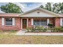 Charming red brick home featuring a well-maintained front yard, white shutters and inviting front door at 414 Cactus Cir, Seffner, FL 33584