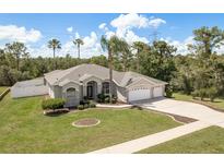Attractive single-story home featuring a well-manicured lawn and a three car garage at 6129 Schalekamp Dr, Spring Hill, FL 34609