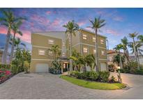 Charming three-story home with a paver driveway, lush landscaping, and multiple palm trees against a beautiful twilight sky at 614 Norton St, Longboat Key, FL 34228