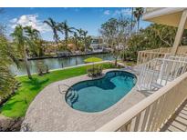 Lush backyard with a kidney-shaped pool and umbrella-covered table, overlooking a serene waterway at 614 Norton St, Longboat Key, FL 34228