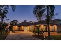Beautiful home exterior with lush palm trees and a well-manicured lawn at dusk at 632 S Florida Ave, Tarpon Springs, FL 34689