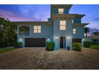 Beautiful blue two-story home with a brick driveway and well manicured landscaping at 7115 Bay St, St Pete Beach, FL 33706