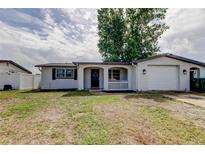 Charming single-story home with an attached garage, front yard, and white picket fence, enhancing curb appeal at 9120 Lunar Ln, Port Richey, FL 34668