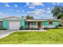 Charming single-story home with a well-manicured lawn, bright exterior, and a driveway leading to an attached garage at 11250 108Th Ln, Largo, FL 33778