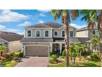 Charming two-story home featuring a brick driveway and lush tropical landscaping at 11419 Emerald Shore Dr, Riverview, FL 33579