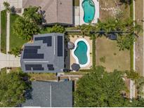 Aerial view showcasing a home with a private pool, solar panels, and lush landscaping at 1213 Barmere Ln, Brandon, FL 33511
