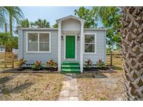 Charming cottage-style home featuring a light-gray exterior, green door, and landscaped front yard at 1527 E Lake Ave, Tampa, FL 33610