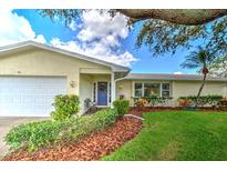 Inviting front entrance with a blue door, manicured bushes, and mulch landscaping at 2132 Sandpiper Dr, Clearwater, FL 33764