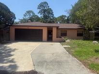 Cozy one-story home featuring a two-car garage and a well-maintained front yard at 4940 Cherry Ct, New Port Richey, FL 34652