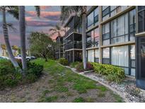 Three story condo with screened balconies surrounded by tropical landscaping, palm trees, and beautiful evening skies at 618 Bird Bay S Dr # 111, Venice, FL 34285