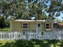 Charming home with a white picket fence and decorative wood shutters, set among mature trees at 8341 June St, Tampa, FL 33615
