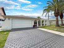 Charming single-Gathering home featuring a two-car garage, decorative archways, and mature palm trees at 9907 Island Harbor Dr, Port Richey, FL 34668