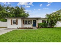 Charming home featuring a well-maintained lawn and a welcoming front porch with blue front door at 1011 N Paddock Ave, Tampa, FL 33607
