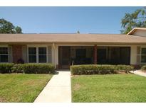 Inviting single-story home with a well-manicured lawn and a charming, screened-in front porch at 1126 Tarridon Ct, Dunedin, FL 34698