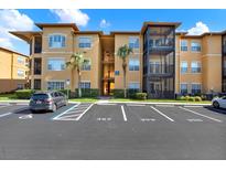 Tan condo building featuring parking lot, palm trees, accessible parking, and screened in terraces at 4333 Bayside Village Dr # 110, Tampa, FL 33615