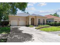 Charming home featuring a two-car garage, brick driveway, manicured landscaping, and a welcoming entrance at 4518 W Woodmere Rd, Tampa, FL 33609
