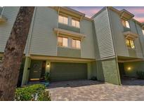 Inviting multi-story home features an attached garage, lush landscaping, and brick paved driveway at 511 Sandy Hook Rd, Treasure Island, FL 33706