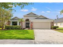 Charming single-Gathering home featuring a manicured lawn, brick accents, and a two-car garage at 9084 Quail Creek Dr, Tampa, FL 33647