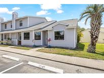 Charming exterior of gray townhouse featuring a palm tree, tidy landscaping, and well-maintained siding at 12648 Castle Hill Dr, Tampa, FL 33624