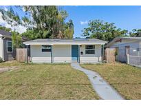 Charming single-story home with a blue front door, solar panels, and freshly painted siding at 1310 43Rd S St, St Petersburg, FL 33711