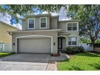 Two story home showcasing a well-manicured lawn, neutral color scheme, attached two car garage and trimmed windows at 3002 Savannah Oaks Cir, Tarpon Springs, FL 34688