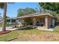 Inviting single-story brick home featuring a cozy front porch and landscaped yard at 314 Bath St, Tarpon Springs, FL 34689