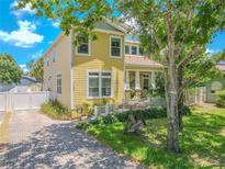 Charming two-story home with yellow siding, landscaped yard, brick driveway, and inviting front porch swing at 316 Lafayette Blvd, Oldsmar, FL 34677