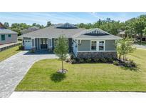 Charming single-story home featuring a landscaped front yard, gray siding, and a brick-paved driveway at 4056 Southern Valley Loop, Brooksville, FL 34601