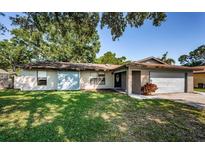 Inviting single-story home with a blue accent door, a well-kept lawn, and an attached garage at 455 Cypress Lake Ct, Oldsmar, FL 34677