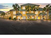 Inviting yellow condo complex with vibrant landscaping, palm trees, and private garages in a desirable neighborhood at 6319 Sunset Bay Cir, Apollo Beach, FL 33572