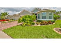 Well-maintained green home featuring lush landscaping and a neatly manicured lawn at 724 Chipper Dr, Sun City Center, FL 33573