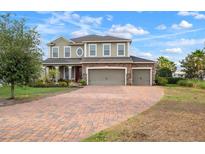 Charming two-story home with a three-car garage and a brick-paved driveway and stone details at 11550 Lake Lucaya Dr, Riverview, FL 33579