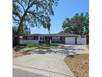Charming single story home with grey and white exterior, mature trees, and extended driveway at 1663 Cambridge Dr, Clearwater, FL 33756