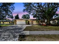 Charming single-story home with a well-manicured lawn, mature trees, and a two-car garage at 1666 Pine Pl, Clearwater, FL 33755