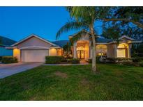 Inviting single-story home featuring lush landscaping, a manicured lawn, and a charming front entrance with double doors at 1802 Oak Ridge Rd, Safety Harbor, FL 34695