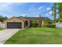 Charming single-story home with a well-manicured lawn, mature landscaping, and an attached two-car garage at 18816 Tracer Dr, Lutz, FL 33549