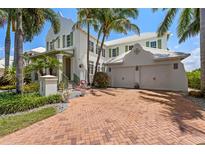 Beautiful two-story white home with green shutters, mature landscaping, and brick driveway at 3125 Christophers Watch Ln, Ruskin, FL 33570