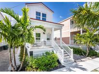 Charming two-story home with a welcoming front porch and beautiful landscaping with palm trees at 340 6Th E St, Bradenton, FL 34208
