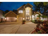 Stately two-story home featuring a large double door entry, three car garage, and manicured landscaping at twilight at 4515 W Leona St, Tampa, FL 33629