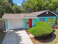 Charming turquoise house featuring a red door, green shrubbery and a well-manicured lawn at 905 8Th Sw Ave, Largo, FL 33770